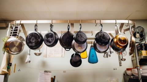 assorted frying pans hanging on pot rack
